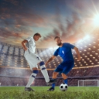 Footballers competing on a floodlit pitch